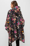 Woman wearing a classic Black Floral Barbour x Tuckernuck Poncho, showcasing an effortless, fun, high-end style with a multicolored floral pattern and hood.