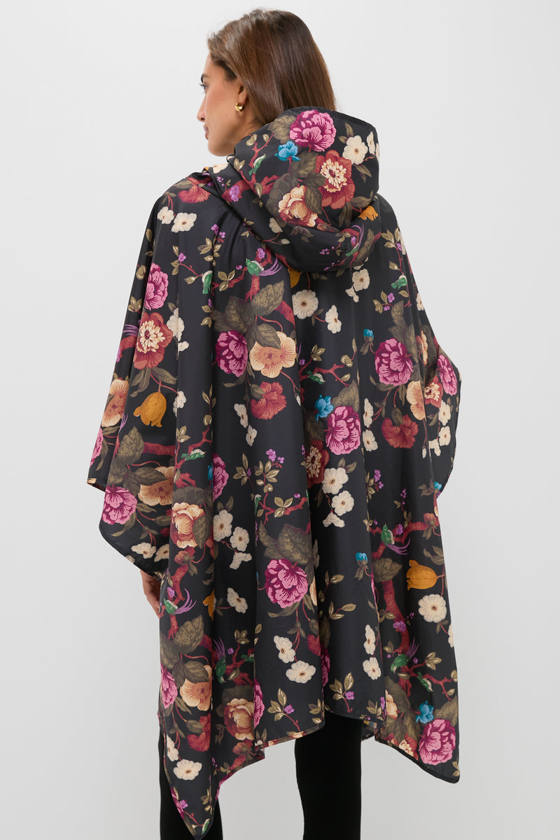 Woman wearing a classic Black Floral Barbour x Tuckernuck Poncho, showcasing an effortless, fun, high-end style with a multicolored floral pattern and hood.