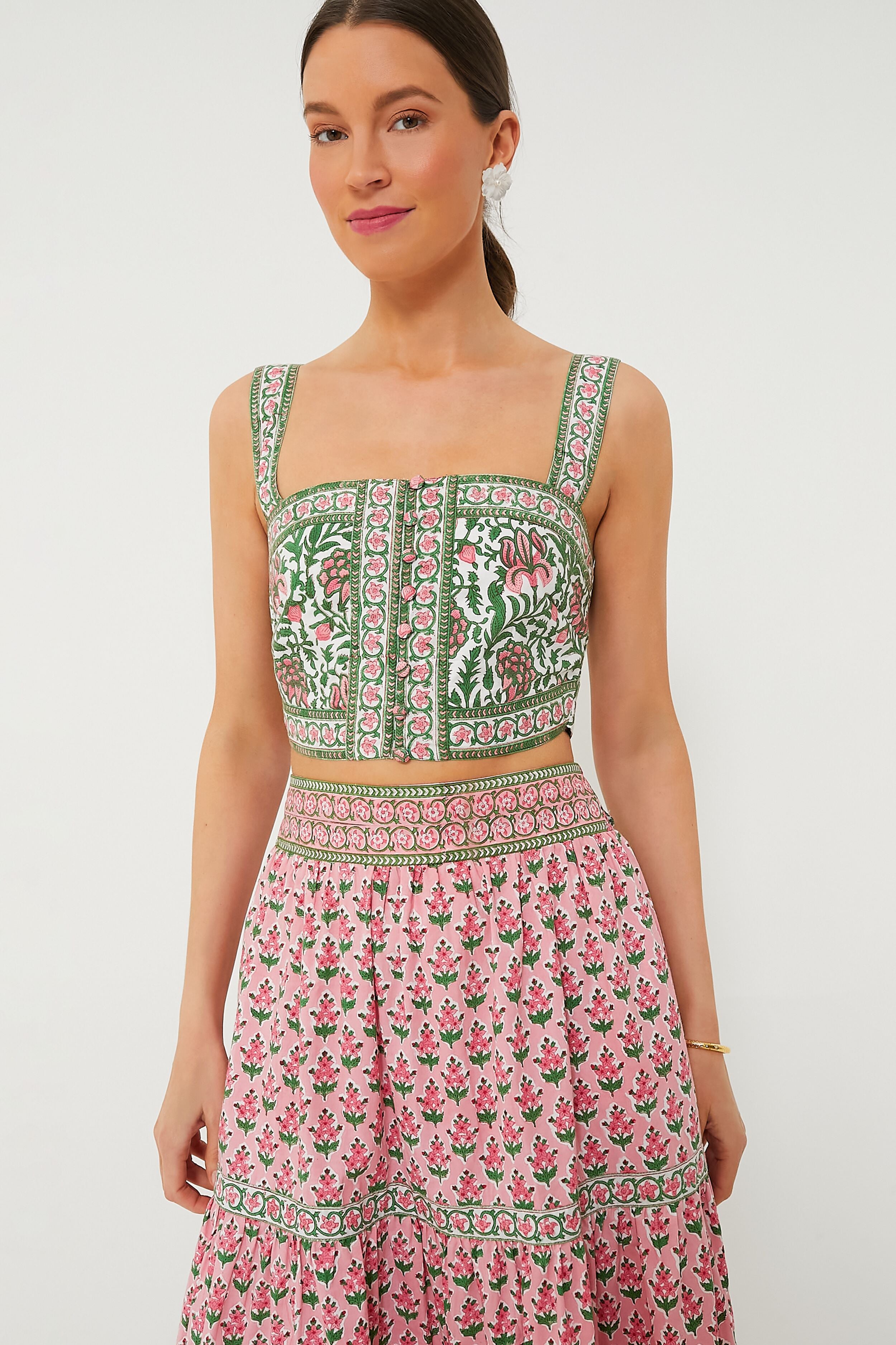 A woman showcases sustainable fashion in a Pink City Prints sleeveless, square-neck block-printed crop top and matching high-waisted skirt with green and pink floral patterns.