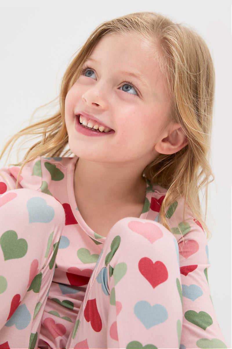 Young girl in a Pink Small Hearts Kids Bamboo Pj Set, showcasing a classic, effortless, and fun bedtime look with a high-end, cozy bamboo fabric.
