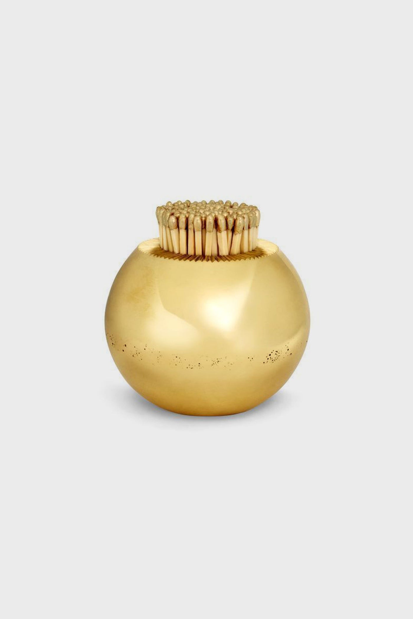 AERIN’s round, shiny gold container, crafted from solid brass as a match striker, holds upright wooden toothpicks—an elegant piece perfect for artisanal home decor.