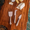 Classic Berry & Thread Cheese Knife Assorted Set of 3 on a wooden board with soft cheese, embodying effortless entertaining with a fun, high-end touch.