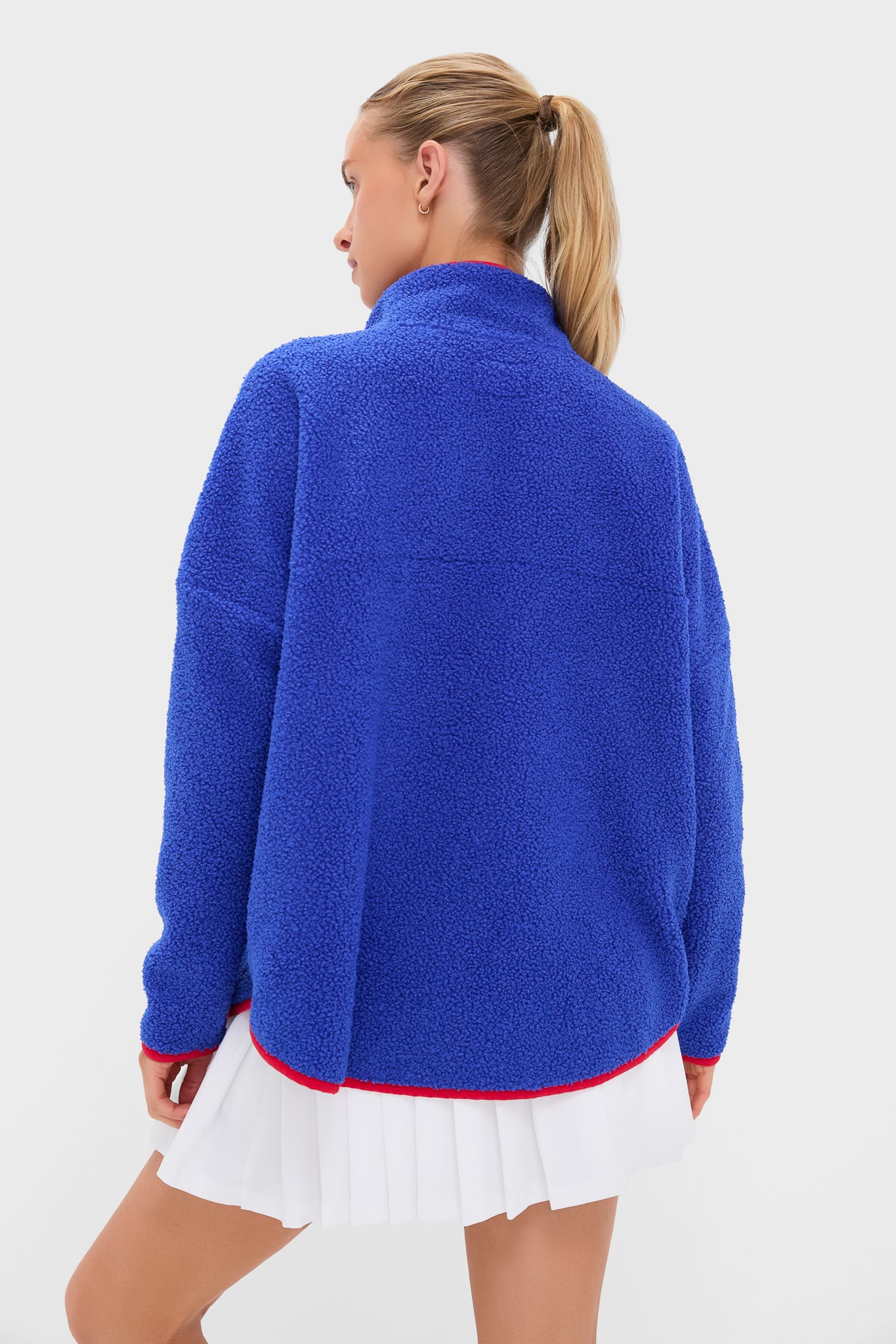 Rear view of a young woman in a classic, effortless Blue and Red Fleece Cady Quarter Zip with a fun, high-end sherpa texture and standout red trim.