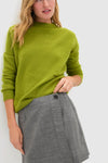 Heathered Grey Marta Mini Skirt with wrap detail, button closure, and back welt pocket, styled with a bright sweater for a classic, effortless, and high-end look.