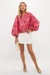 A woman wears a Hyacinth House red and white floral jacquard puff sleeve blouse with a white skirt.