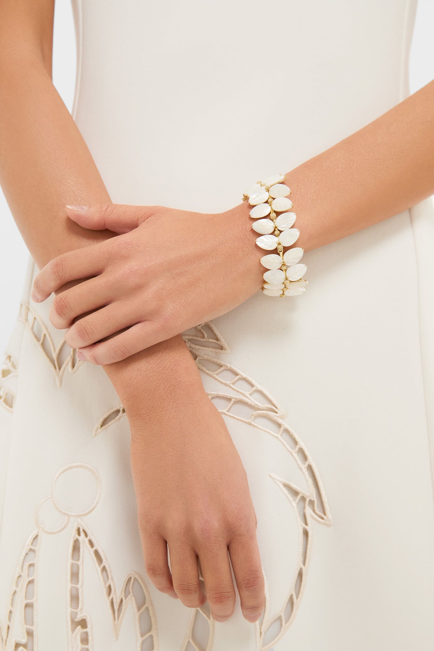 Woman's forearms adorned with the Mermaid Garden Vine Bracelet, featuring classic mother of pearl leaves and golden accents, embodying an effortless, high-end bohemian elegance.