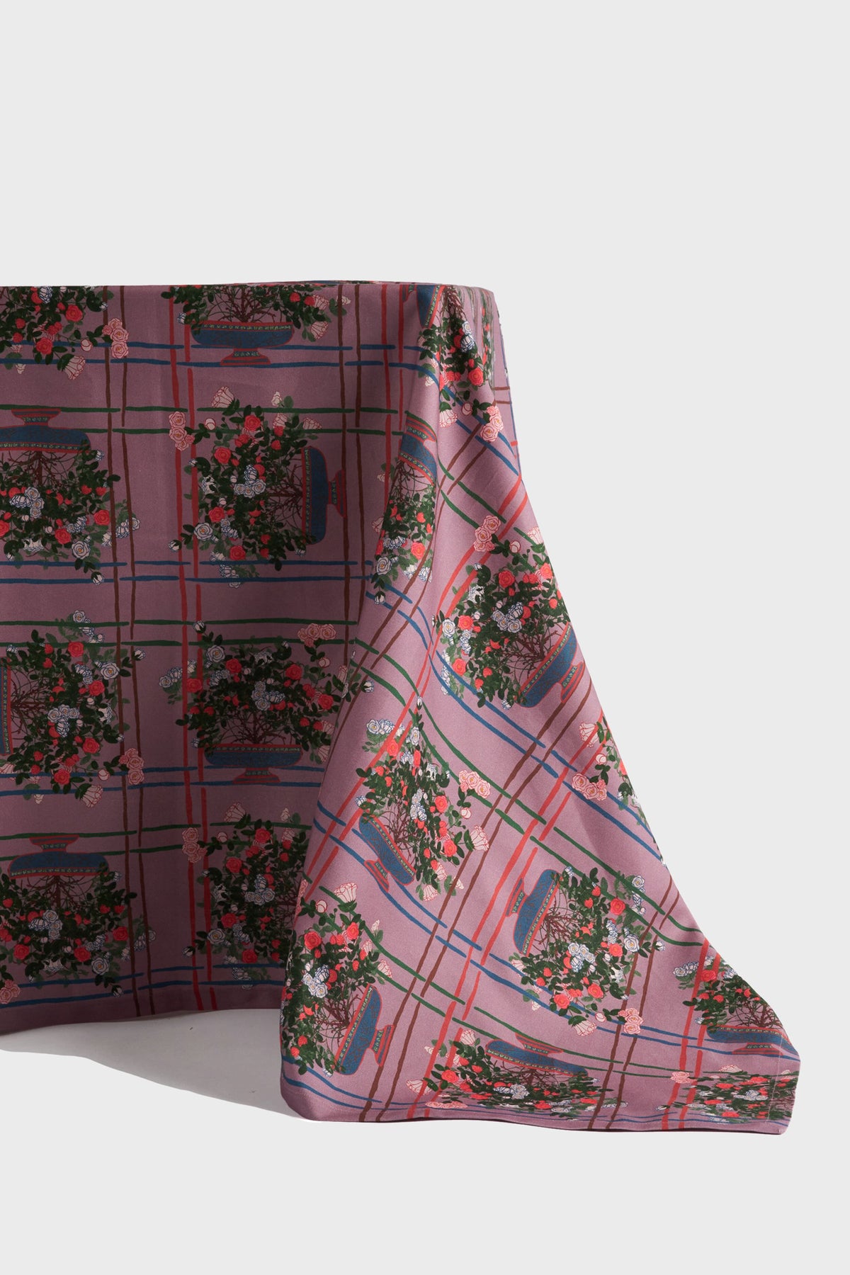 A sustainable tablecloth from Sophie Williamson Design featuring a pink and red plaid pattern with basket and floral motifs—perfect for adding eco-friendly charm to your home décor.