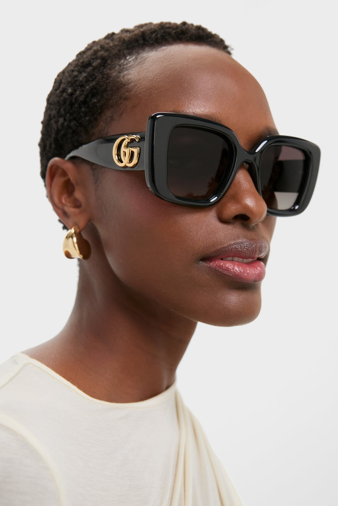 Sleek Black Square GG Sunglasses on a dark-skinned model, featuring classic gradient lenses and gold Gucci logo, offering an effortless, high-end style for any occasion.
