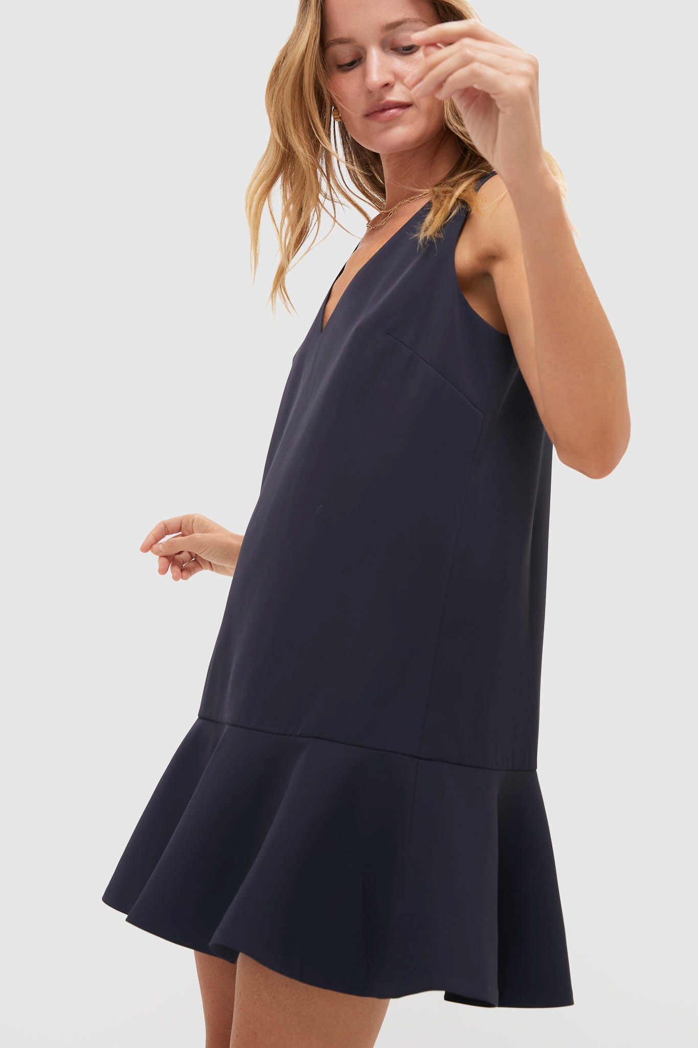 Model wearing the Dark Slate Navy Flutter McKinney Mini Dress, an effortless, classic piece with a swing silhouette and flutter hem, embodying high-end, fun style.