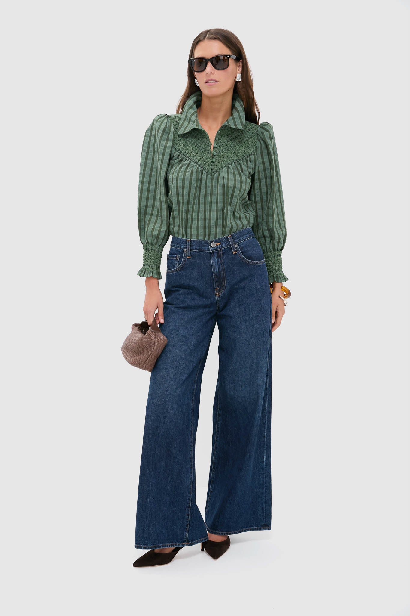 Woman models the Green Windowpane Seersucker Vail Blouse with classic smocking details, paired effortlessly with wide-leg jeans and a textured handbag for a high-end, fun look.