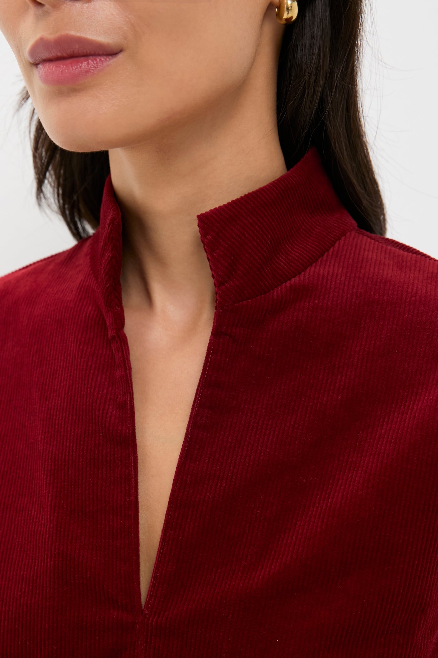 Close-up of a woman wearing the Merlot Corduroy Clifton Dress, showcasing its classic stand collar and V-neckline for an effortlessly chic, high-end look.