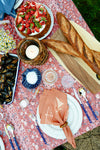 A summer table with a cake covered in strawberries, mussels, and two baguettes. 