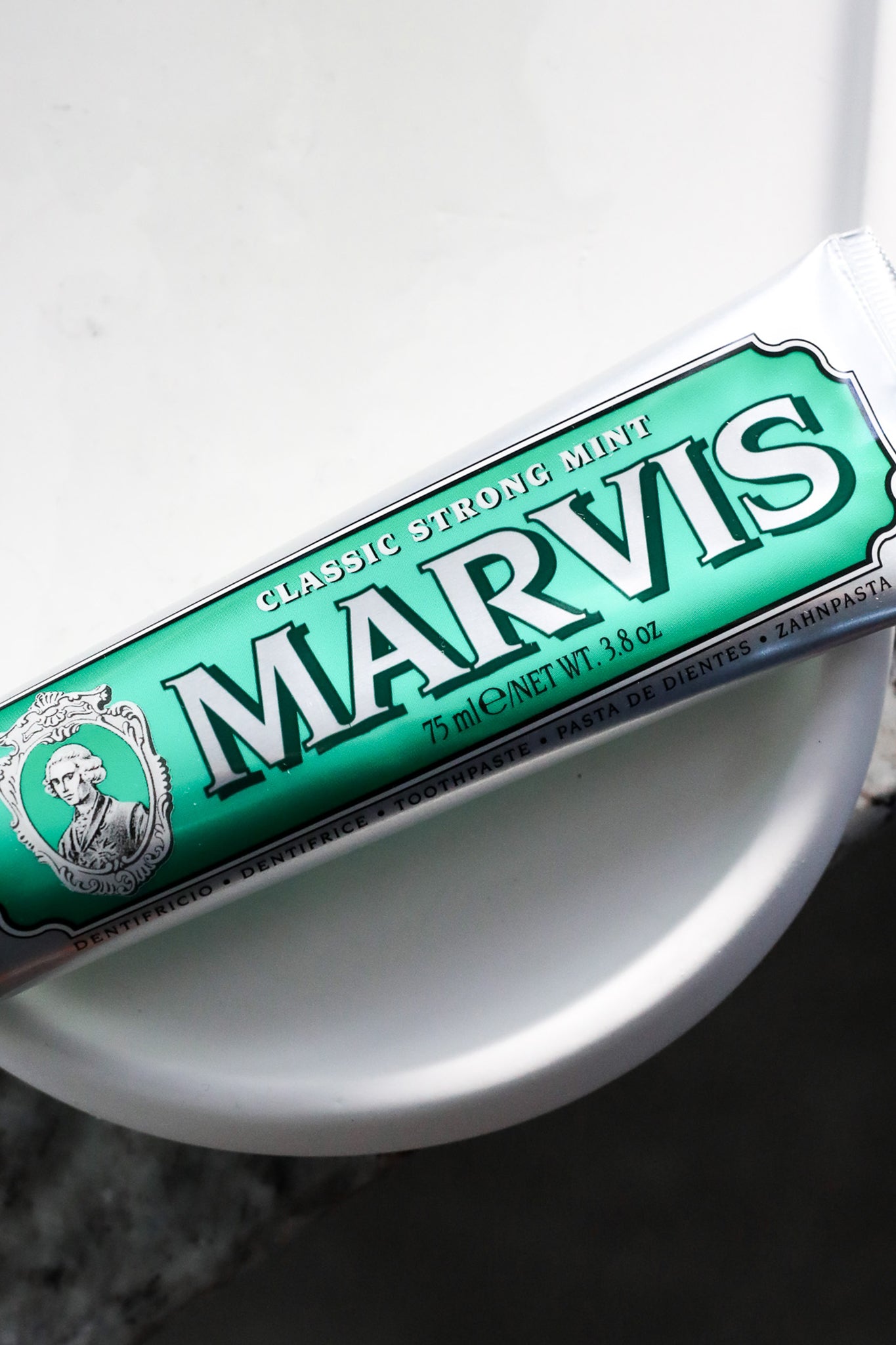 Marvis Classic Strong Mint toothpaste tube on white ceramic, offering effortless, high-end dental care with fun, classic mint freshness for long-lasting clean and confident breath.