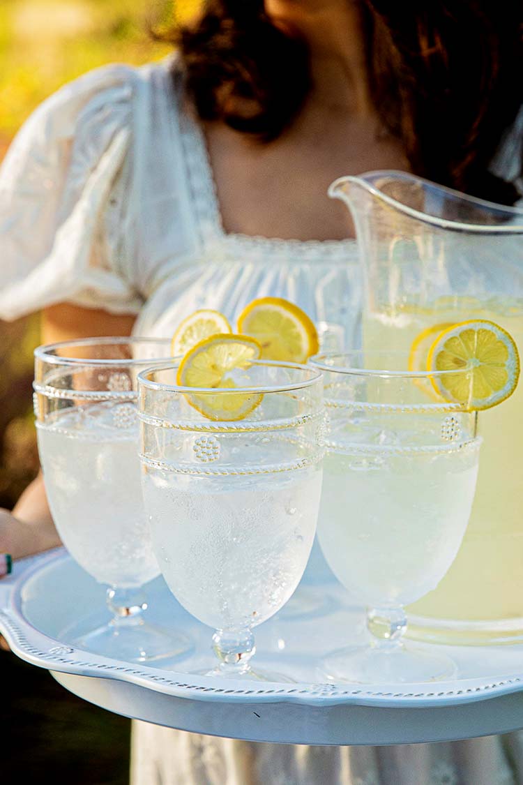 Isabella Acrylic Goblet Set of 4 on a white tray, featuring classic stemmed glasses with lemon garnish, embodying effortless, fun, high-end entertaining.