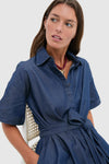 Young woman in a classic Dark Denim Zacara Dress, featuring a button-front, self-tie belt, and drop shoulders, embodying effortless, fun, high-end style.