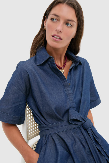 Young woman in a classic Dark Denim Zacara Dress, featuring a button-front, self-tie belt, and drop shoulders, embodying effortless, fun, high-end style.