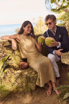 Couple enjoying a tropical setting; woman in classic, effortless Blink Square Toe Twiggy Sandals offers coconut, embodying fun, high-end style.