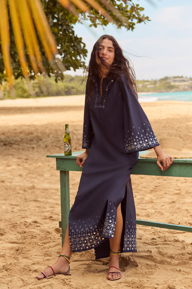 Young woman in a classic navy dress showcases Rainbow Constantia Sandals, featuring multi-colored straps and a wrap-around ankle strap, embodying effortless, high-end summer style.