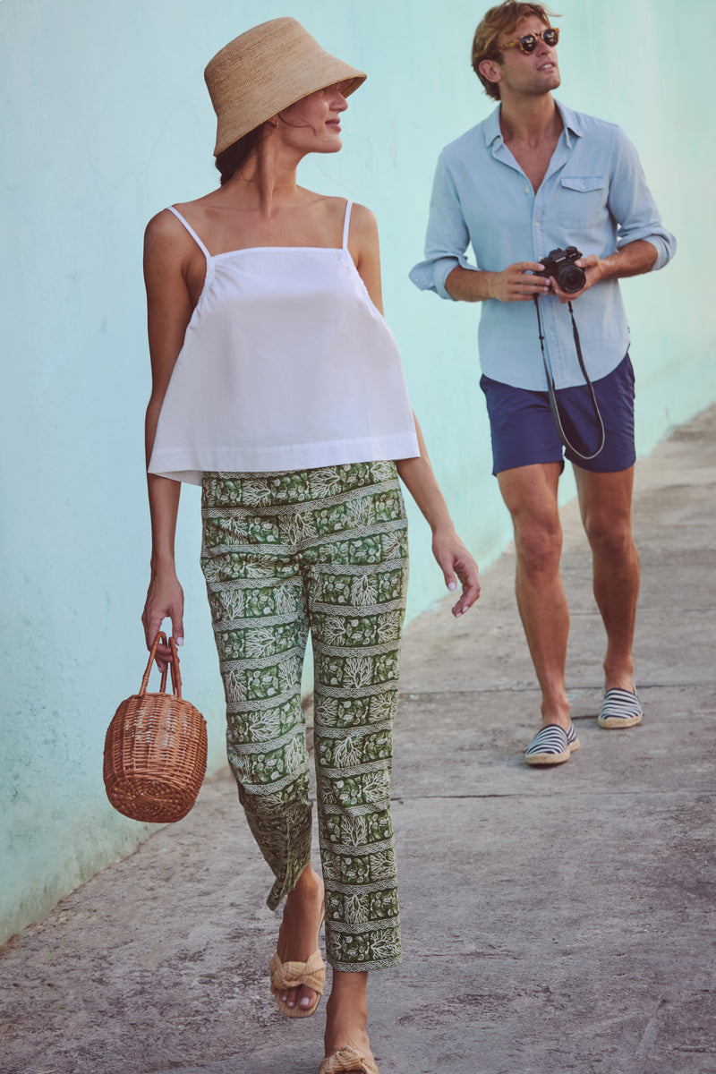 Woman in a classic White Cotton Madi Top with adjustable straps, showcasing an effortless, high-end look, styled with patterned pants, embodying fun and relaxed elegance.