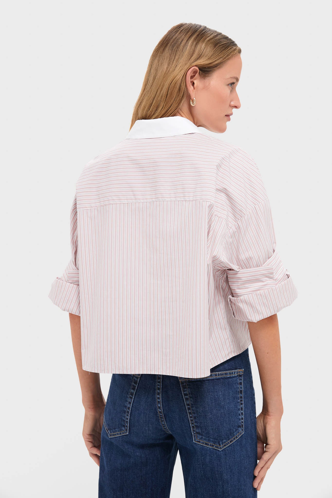 Back view of a person wearing the Spanish Villa and White Next Ex Shirt, a classic, effortless, cropped button-down with rolled sleeves, paired with high-waisted jeans.