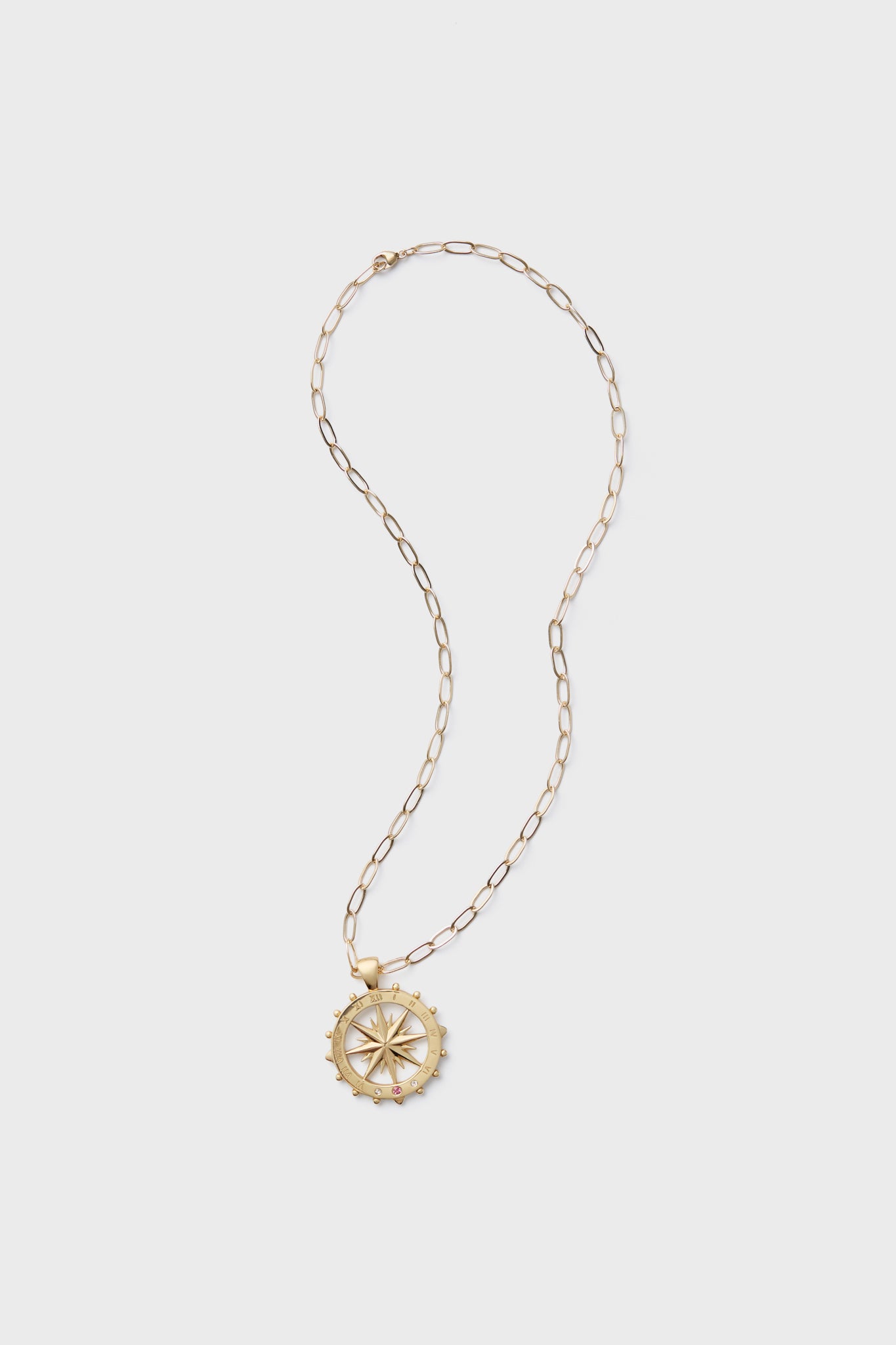 A Jane Win gold chain necklace featuring a round compass rose pendant, detailed design, and white topaz accents.