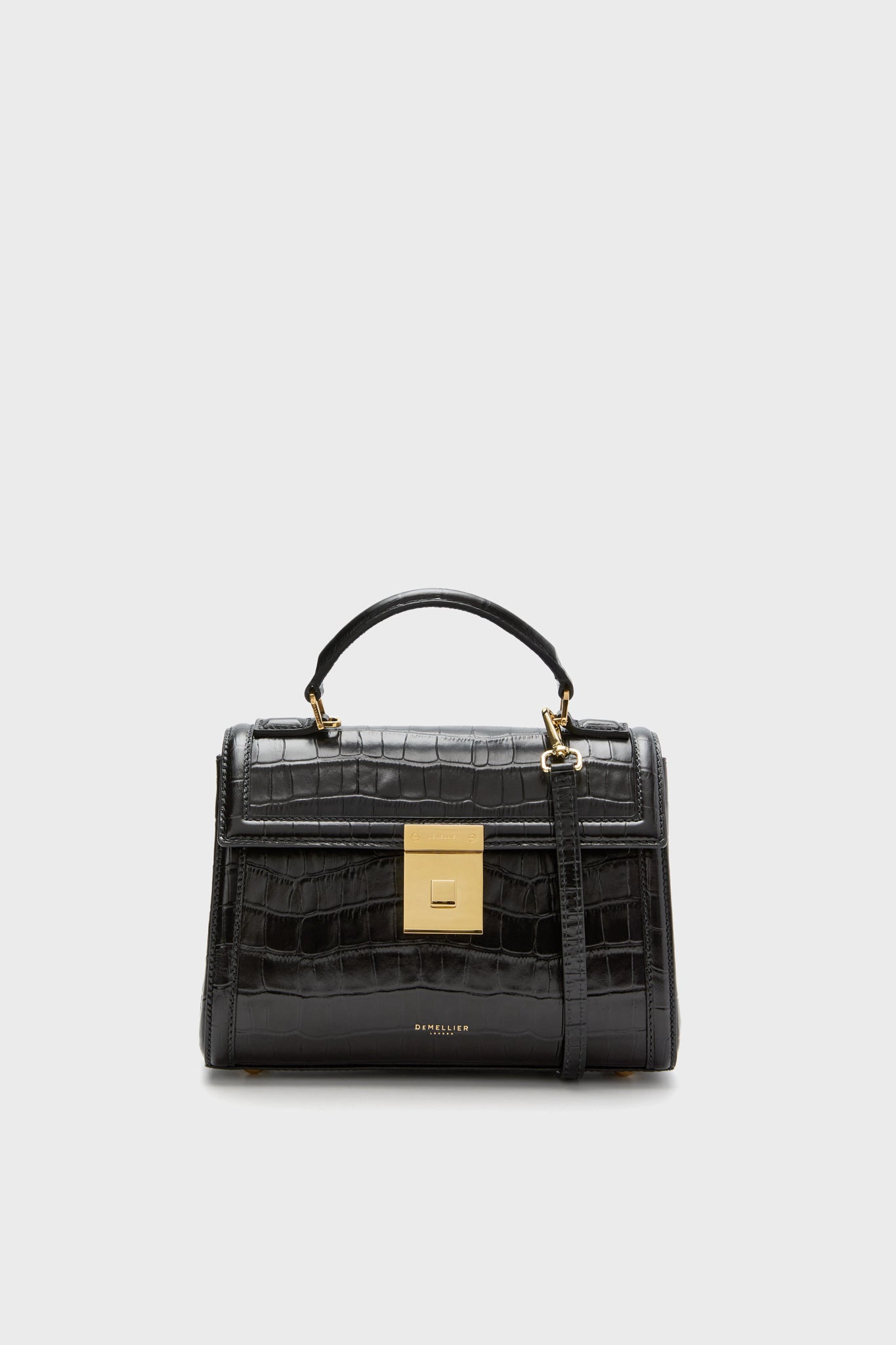 The Demellier Black Croc Paris Bag, handcrafted from sustainable Italian leather, features a top handle, gold square clasp, and a detachable shoulder strap.