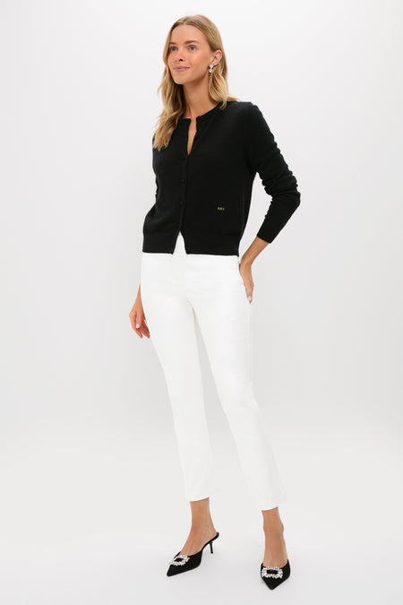 Model showcases classic Winter White Velvet Ashford Pants with a black cardigan, achieving an effortless, high-end look, complemented by black mule heels with jeweled buckles.