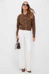 Model in a classic, high-end Brown Morgan Cardigan with gold-tone crystal buttons, styled effortlessly with white trousers and tortoiseshell pumps for a fun, polished look.