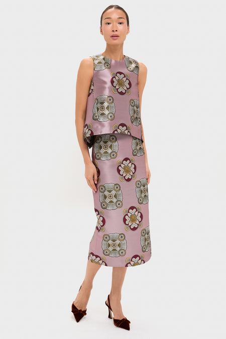 A woman wears a sleeveless pink La DoubleJ top with a matching nucleus-print silk jacquard midi skirt featuring owl and floral motifs, paired with brown heels.
