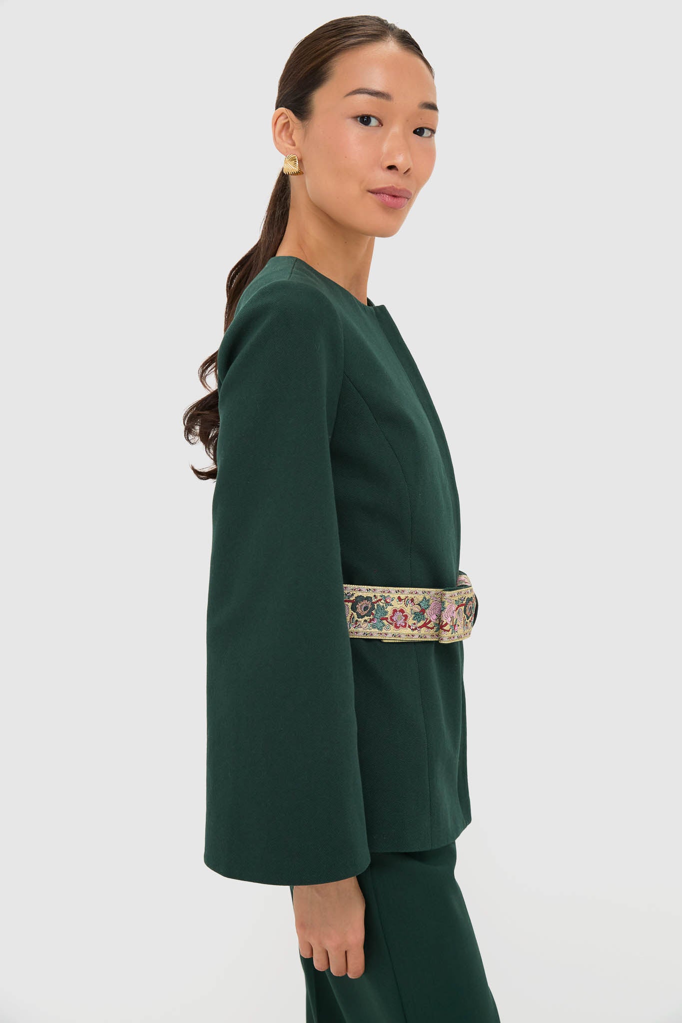 Woman in profile wearing the Garden Scrollwork Jacquard Belted Rhoda Tunic Top, showcasing its classic, high-end style with an effortless, fun jacquard belt and sculptural earring.
