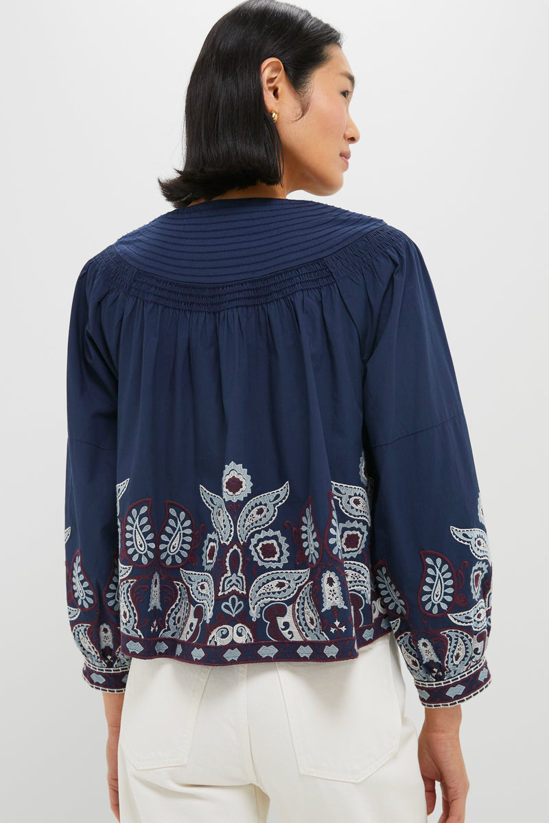 Navy Embroidered Lucia Blouse, classic and effortless with pintucks, embroidered hem, and puff sleeves. Paired with high-waisted jeans for a fun, high-end look.