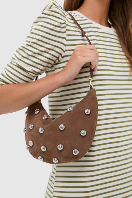 Woman wearing a striped top holds the classic, high-end Choco Bar Smooth Nubuck with Studs Lune Bag, featuring effortless silver studs and a fun, knotted strap.