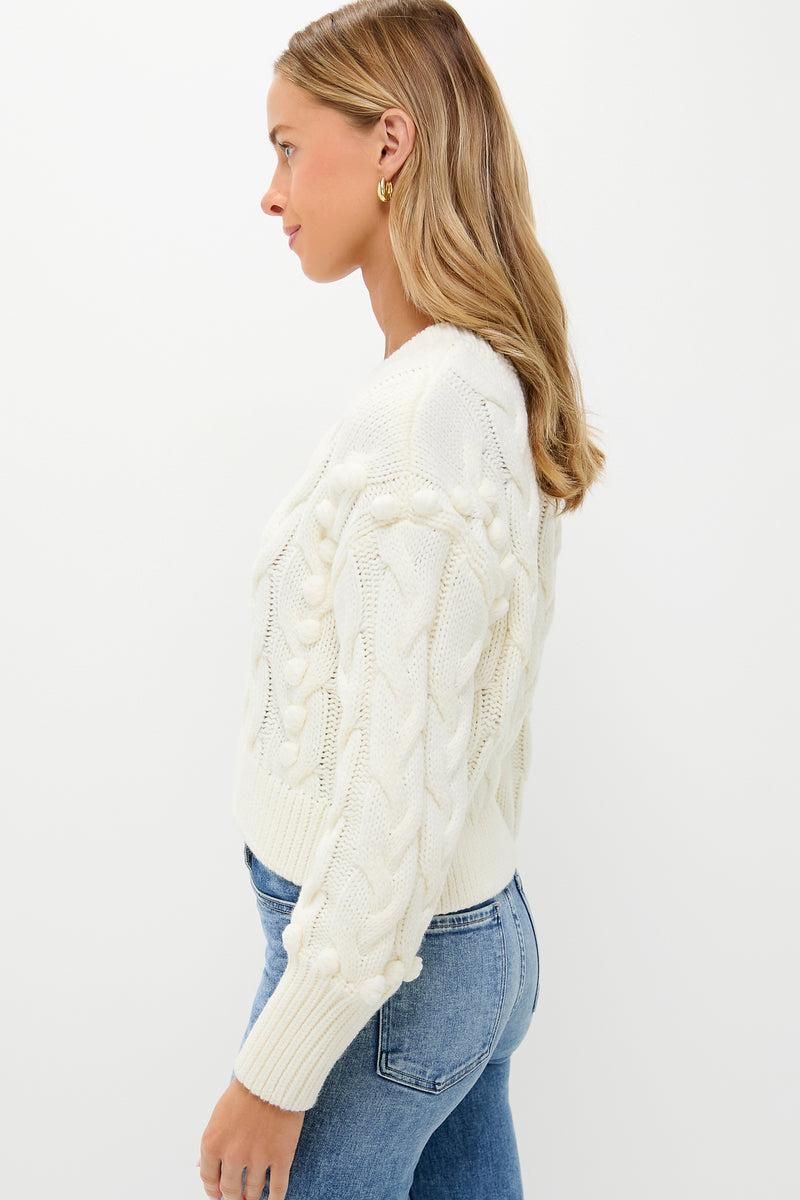 Side-profile of a woman wearing the Ivory Cable Knit Cropped Contessa V-Neck Sweater, showcasing its classic, effortless design with chunky knit and drop shoulders, paired with jeans.