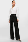 Woman in classic, high-end Black Sequin Tatum Pants, featuring effortless wide-leg design paired with a crisp blouse and minimal gold jewelry, exuding fun sophistication.