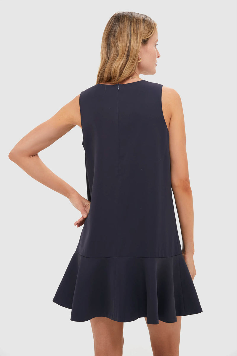 Back view of a woman in a classic, effortless Dark Slate Navy Flutter McKinney Mini Dress, featuring a swing silhouette and flutter hem, embodying high-end, fun style.