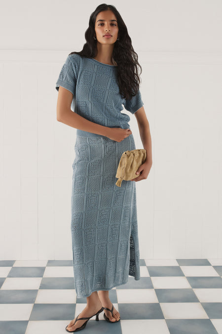 Woman in a matching crochet skirt set in blue. 