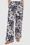 Wearing La DoubleJ wide-leg pants in navy blue with a white and beige floral print, this person stands with hands in pockets and flat sandals.