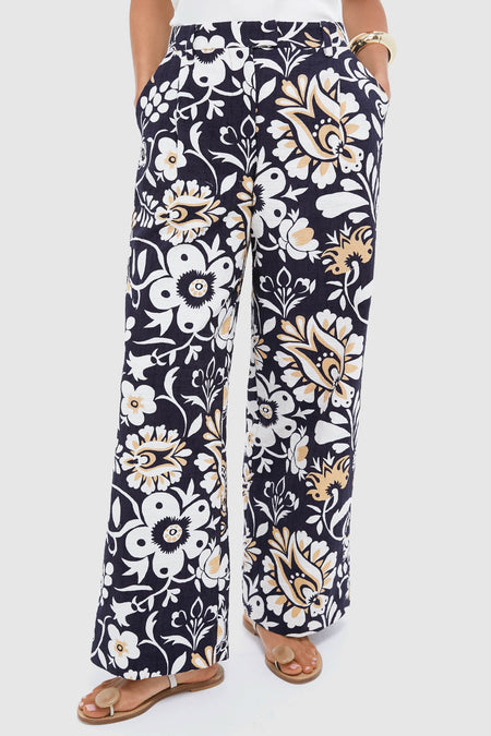 Wearing La DoubleJ wide-leg pants in navy blue with a white and beige floral print, this person stands with hands in pockets and flat sandals.