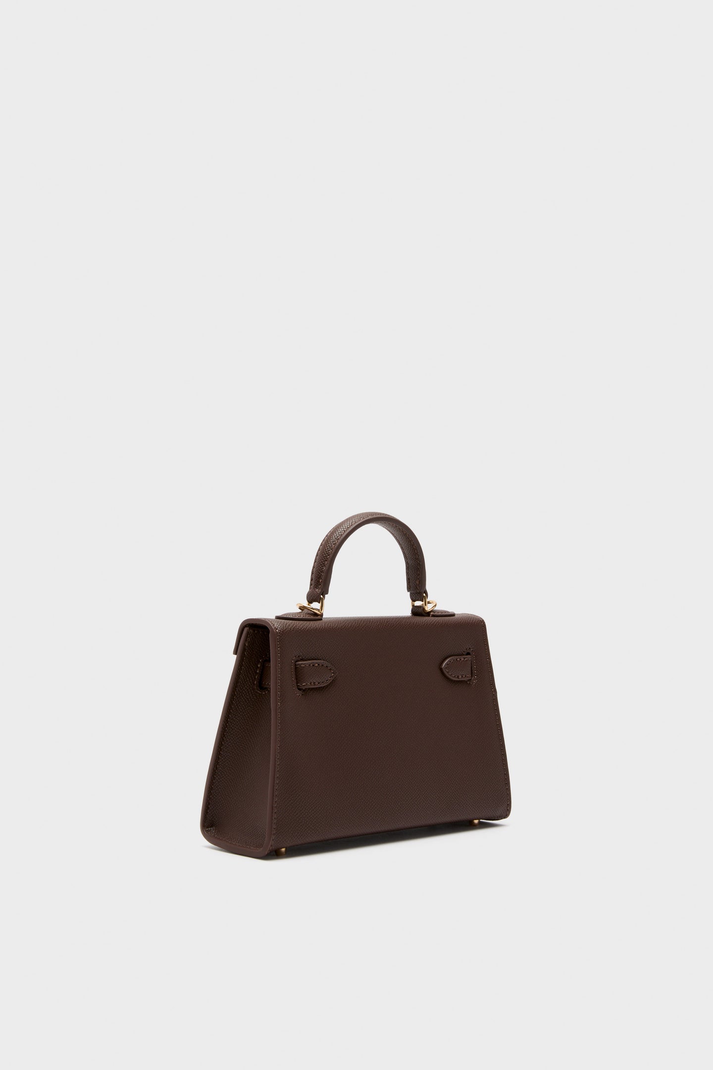 Chocolate Hariette Handle Bag in dark brown pebbled leather with a classic trapezoidal shape, gold hardware, and top handle. Effortlessly transitions from day to night.