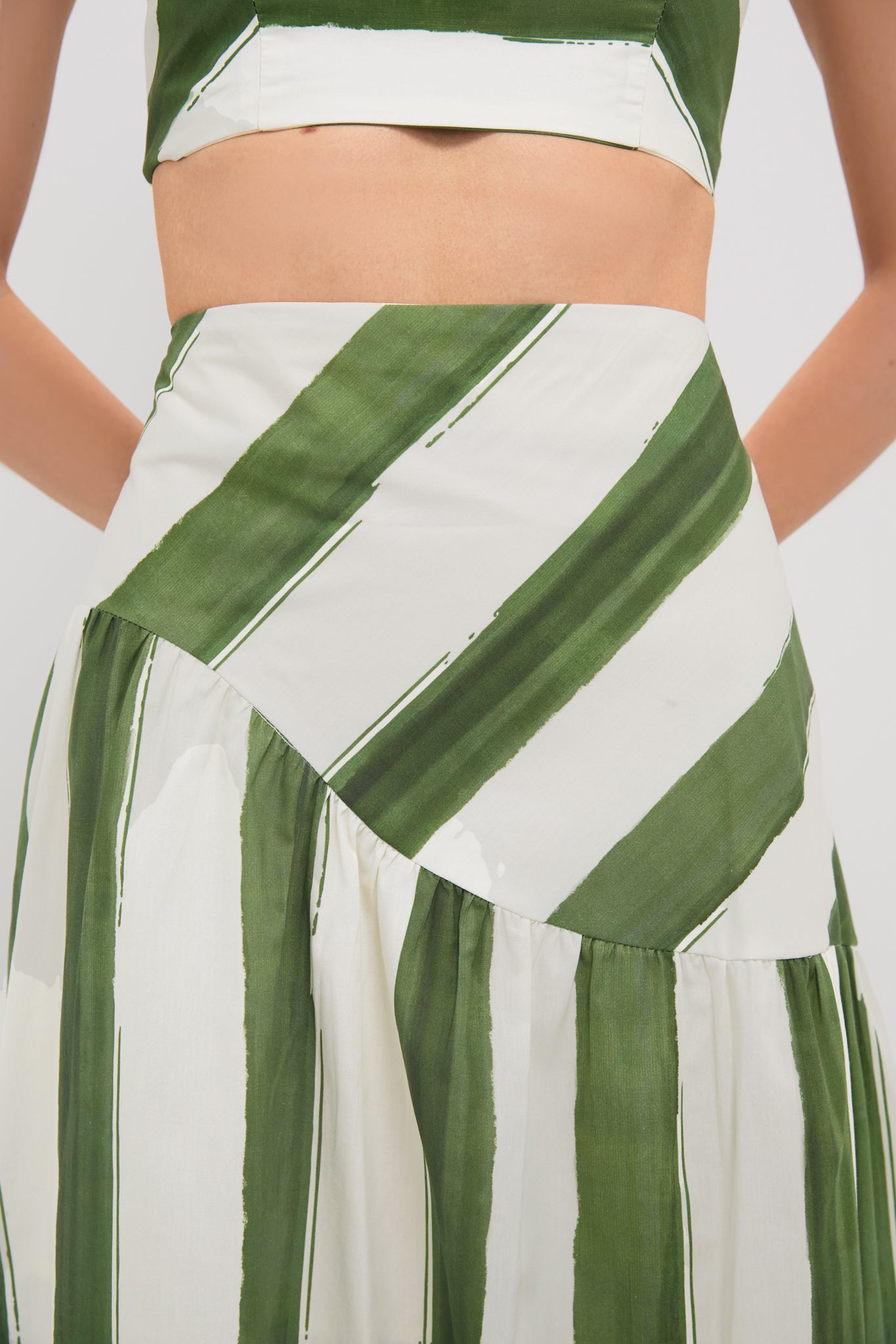 Woman in a classic, effortless Green Stripe Nature Midi Skirt with drop waist and A-line silhouette, paired with matching top for a fun, high-end look.