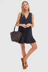 Woman in classic Dark Slate Navy Flutter McKinney Mini Dress with V-neck and flutter hem, styled effortlessly with a woven tote and suede flats for a fun, high-end look.