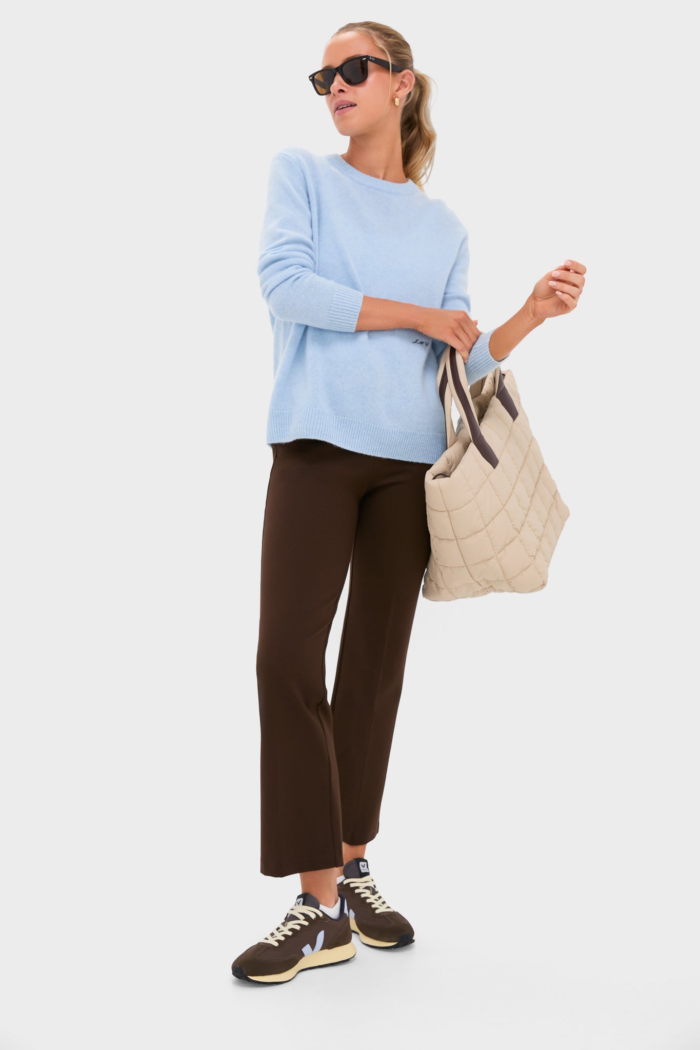 Model in classic, effortless ensemble featuring Chocolate Brown 28 Inch Compression September Pant, styled with a knit sweater, chic sneakers, and a quilted tote, exuding high-end, fun sophistication.