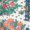 Close-up of a patterned fabric featuring red, orange, and green floral designs with scattered small blue and black accents.