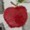 A red apple with a stem and leaf rests on a white surface, its vibrant color standing out beautifully.