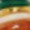 A blurry close-up featuring vibrant red, white, green, and yellow hues with an indistinct object at the center.