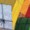 Four colored pencils—yellow, orange, red, and green—are arranged next to an open spiral notebook with lined paper.