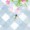 A small black ant crawls on a light blue and white checkered surface decorated with pink and green floral patterns, adding a touch of nature to the scene.