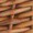 Close-up view of a woven wicker or rattan pattern, highlighting the intricate interlaced strips of natural brown material.