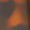 Blurry image with abstract shapes in dark purple and orange hues, possibly depicting an out-of-focus light source or digital glow.