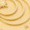 A close-up of smooth, light beige sand with concentric circular patterns and a small rake at the top left corner evokes the tranquility of a zen garden.